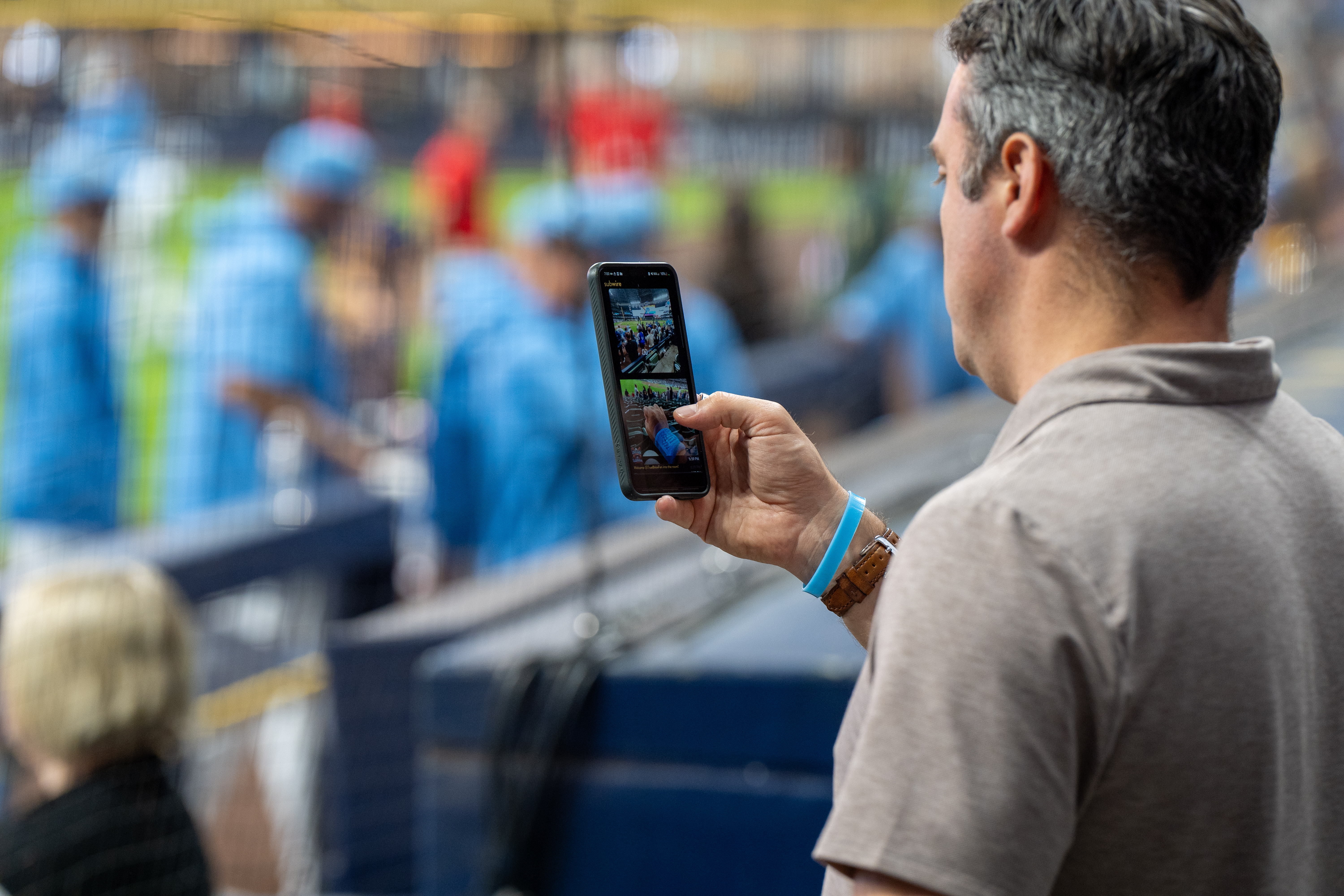 Fan casually looks on to capture content at MLB stadium on SubWire.